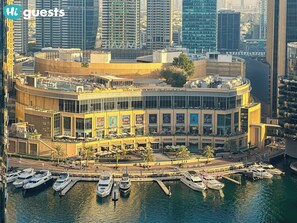 A waterfront building with multiple balconies, a marina with yachts, and a prominent sign for Dubai Marina Mall. - HiGuests - Bahar 6 (Dubai)