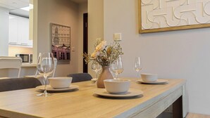 A dining table set with white bowls and wine glasses, a vase with flowers, and a wall-mounted abstract art piece.