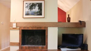 A living room with a fireplace, a framed picture on the wall, and a television on a stand.