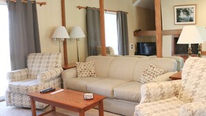 A living room with a sofa, armchairs, a coffee table, and lamps.