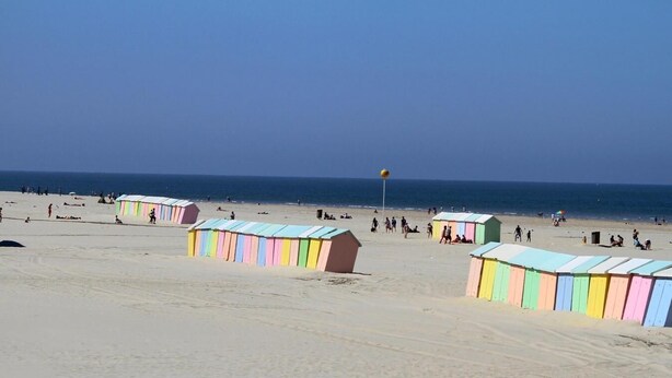 Een strand met kleurrijke strandhutten en mensen die genieten van het zand en de zee.