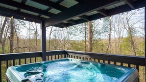A hot tub on a wooden deck with a view of trees. - Home theater, hot tub, pool table, secluded, spacious. (Gatlinburg)
