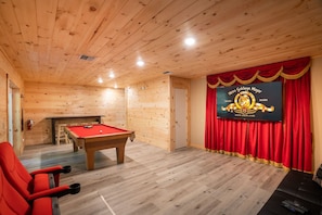 Une pièce en bois avec une table de billard, des rideaux rouges et une bannière accrochée au mur.