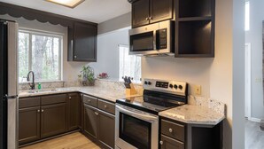 A modern kitchen with dark cabinets, stainless steel appliances, and a granite countertop. - Home theater, hot tub, pool table, secluded, spacious. (Gatlinburg)