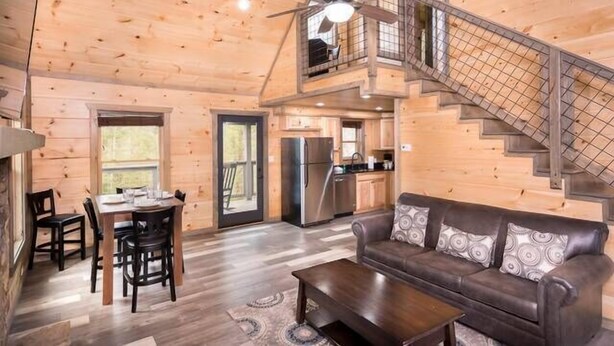 Een ruime houten chalet met een eethoek, een bank en een keuken.