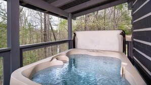 Een hottub in een overdekte buitenruimte met uitzicht op bomen.