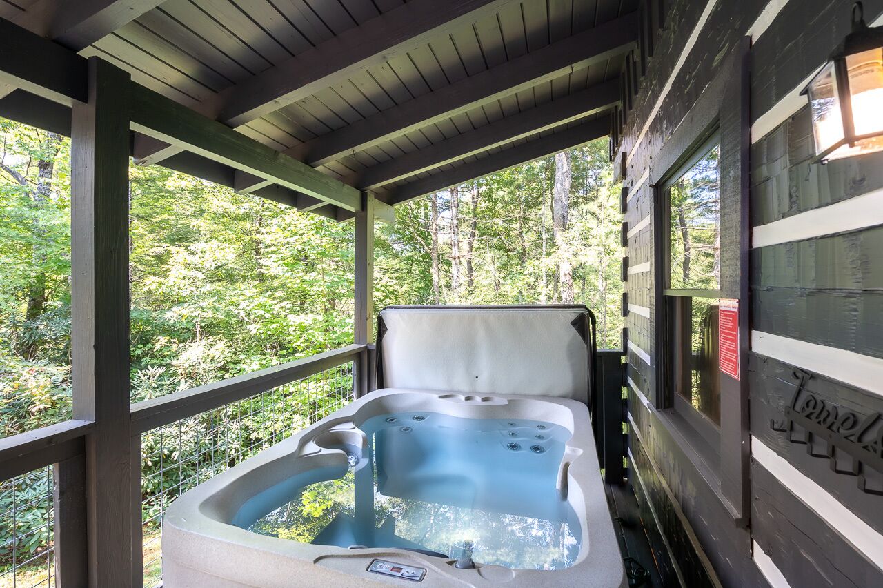 A hot tub in a covered outdoor area with a view of a forest.