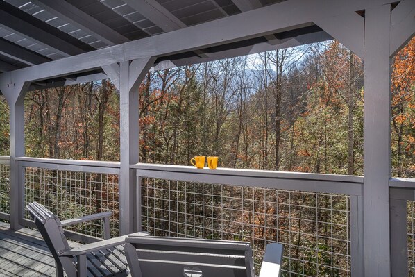 Ein überdachter Außenbereich mit Holzterrasse, Metallgeländer und zwei Stühlen.