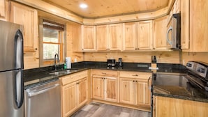 Eine moderne Küche mit Holzschränken, Edelstahlgeräten und einer schwarzen Granitabdeckung.