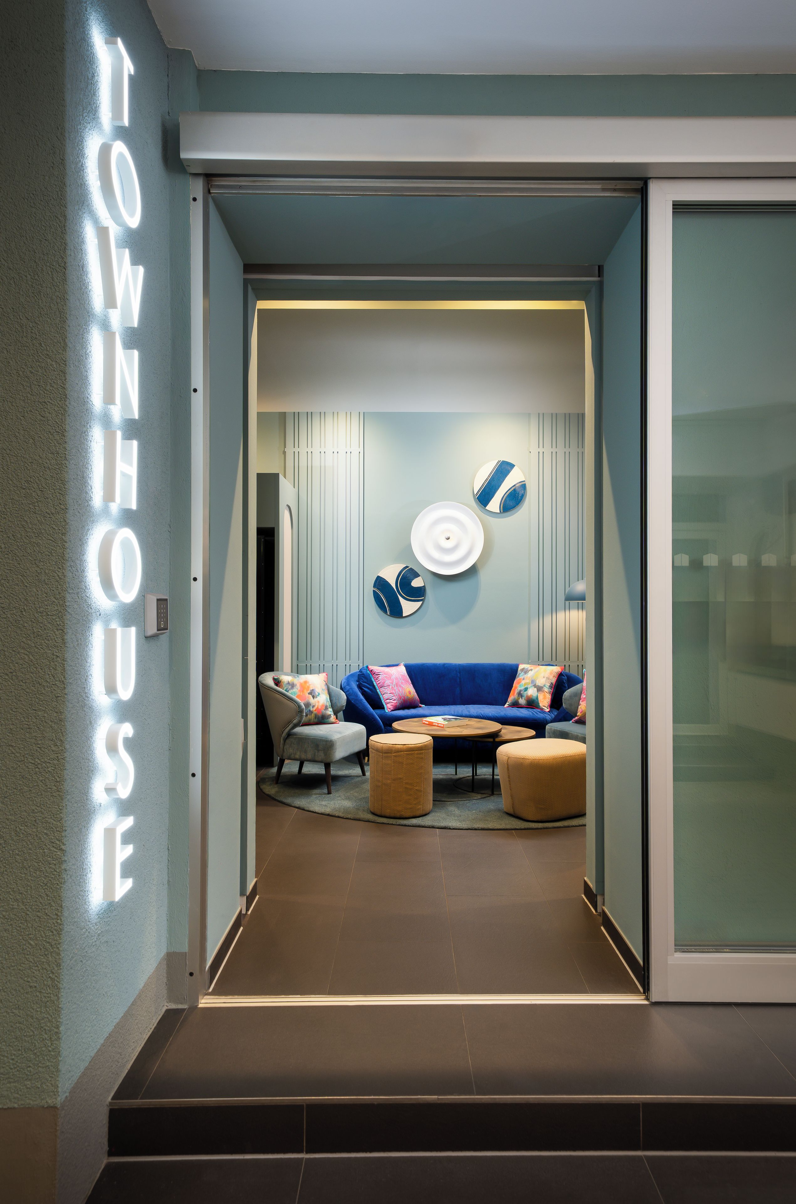 Un interior modern amb un sofà blau, una taula de centre rodona i una làmpada penjant a la paret.