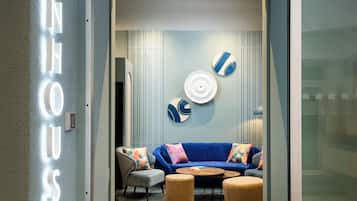 Un interior modern amb un sofà blau, una taula de centre rodona i una làmpada penjant a la paret.