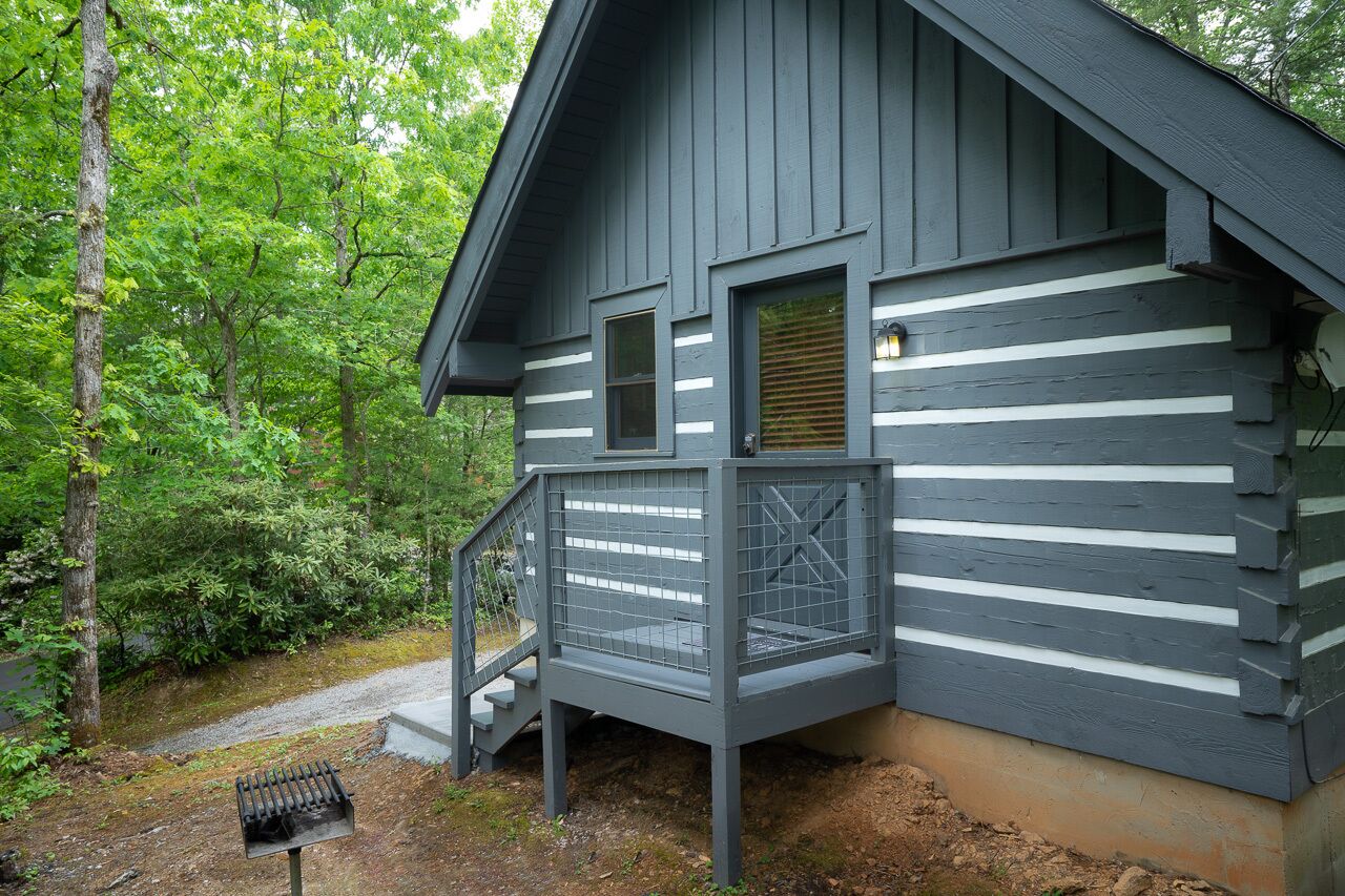 A cabin with a wooden exterior, a porch with a railing, and a small window.