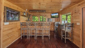 Un interno in legno con un'area bar, diversi posti a sedere e un televisore.