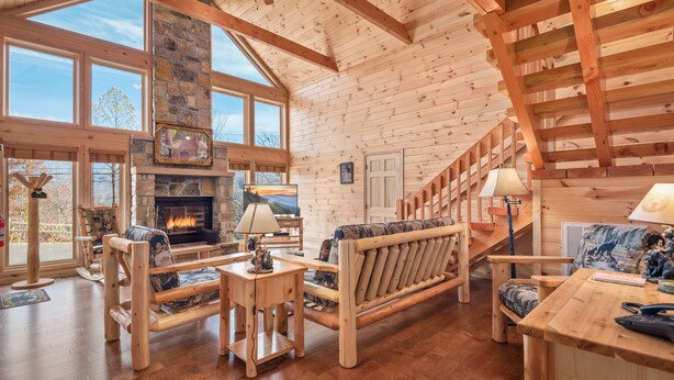 A spacious living room with a fireplace, wooden furniture, and large windows. - 2 King Bedrooms, Jetted Tubs, Screened in Porch, Private Hot tub, Pet Friendly (Gatlinburg)