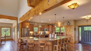Una cocina amplia con una isla grande, taburetes de madera y electrodomésticos modernos.