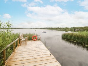 A wooden dock with a bench and a lifebuoy, leading to calm water with kayaks. - Port Heron Lodge (Athlone)