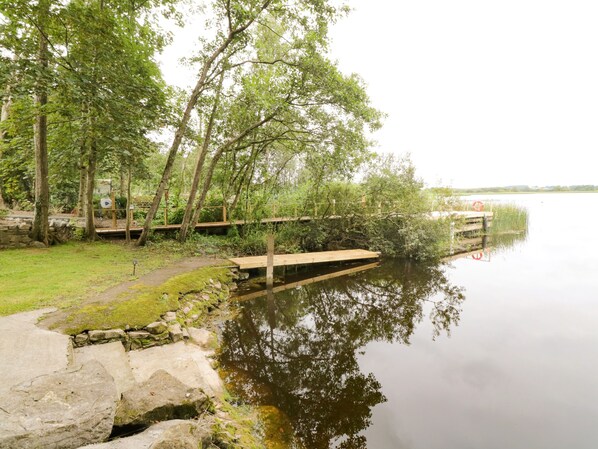 A calm lake with a wooden dock extending into the water, surrounded by lush greenery and trees. - Port Heron Lodge (Athlone)