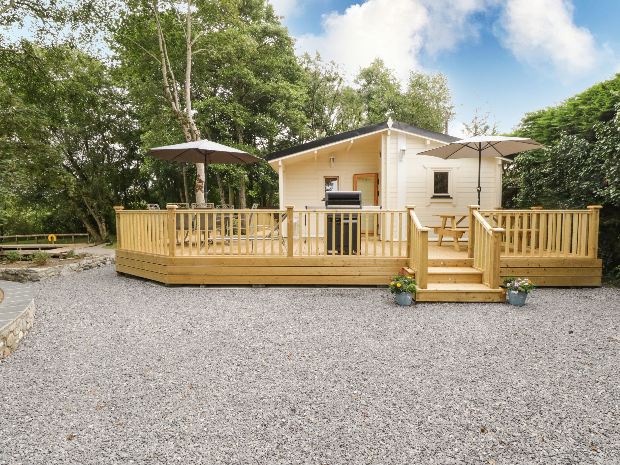 A wooden deck with a barbecue area and outdoor seating.