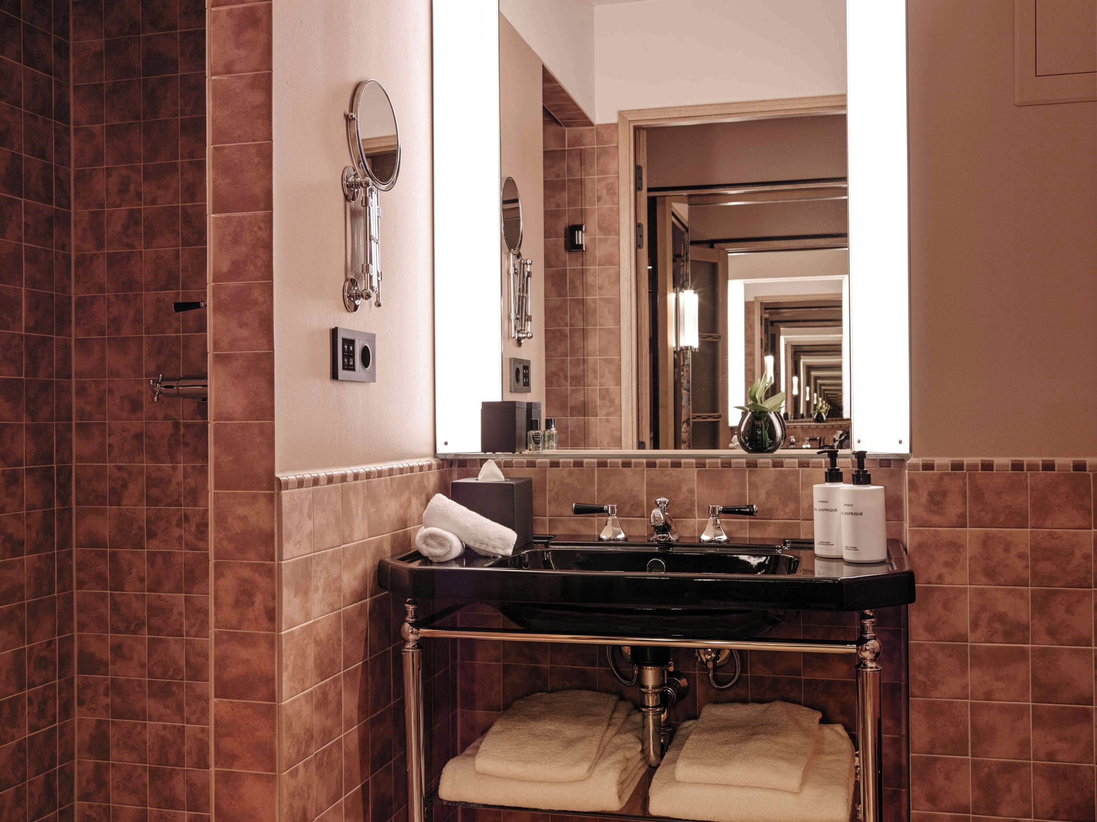 Ein Badezimmer mit einem schwarzen Waschbecken, zwei Handtuchhaltern, einem Spiegel und einer Toilette.