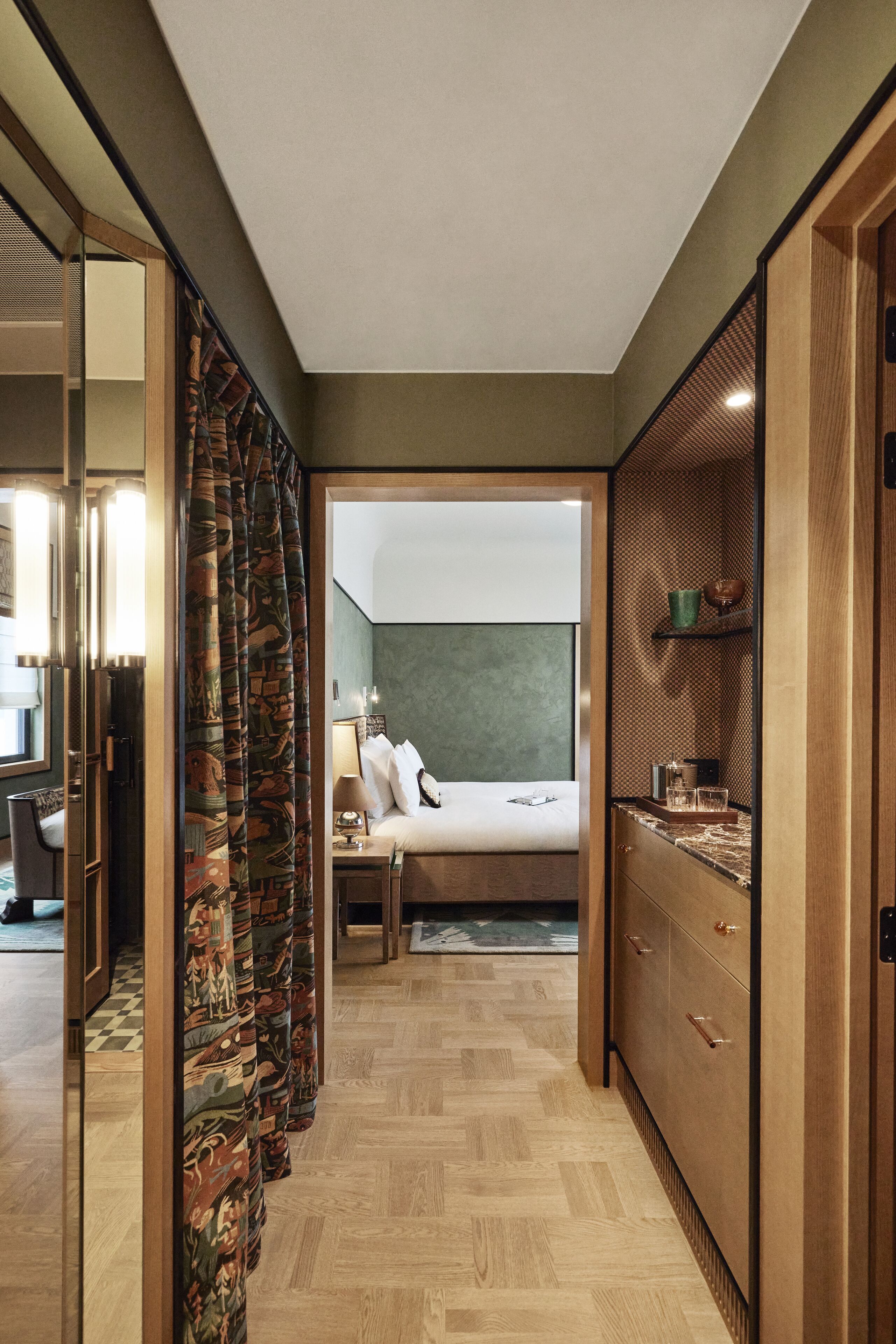 Habitación de hotel con una cama, un armario de madera, una mesita de noche pequeña y un espejo.