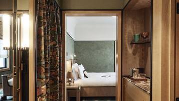 Habitación de hotel con una cama, un armario de madera, una mesita de noche pequeña y un espejo.