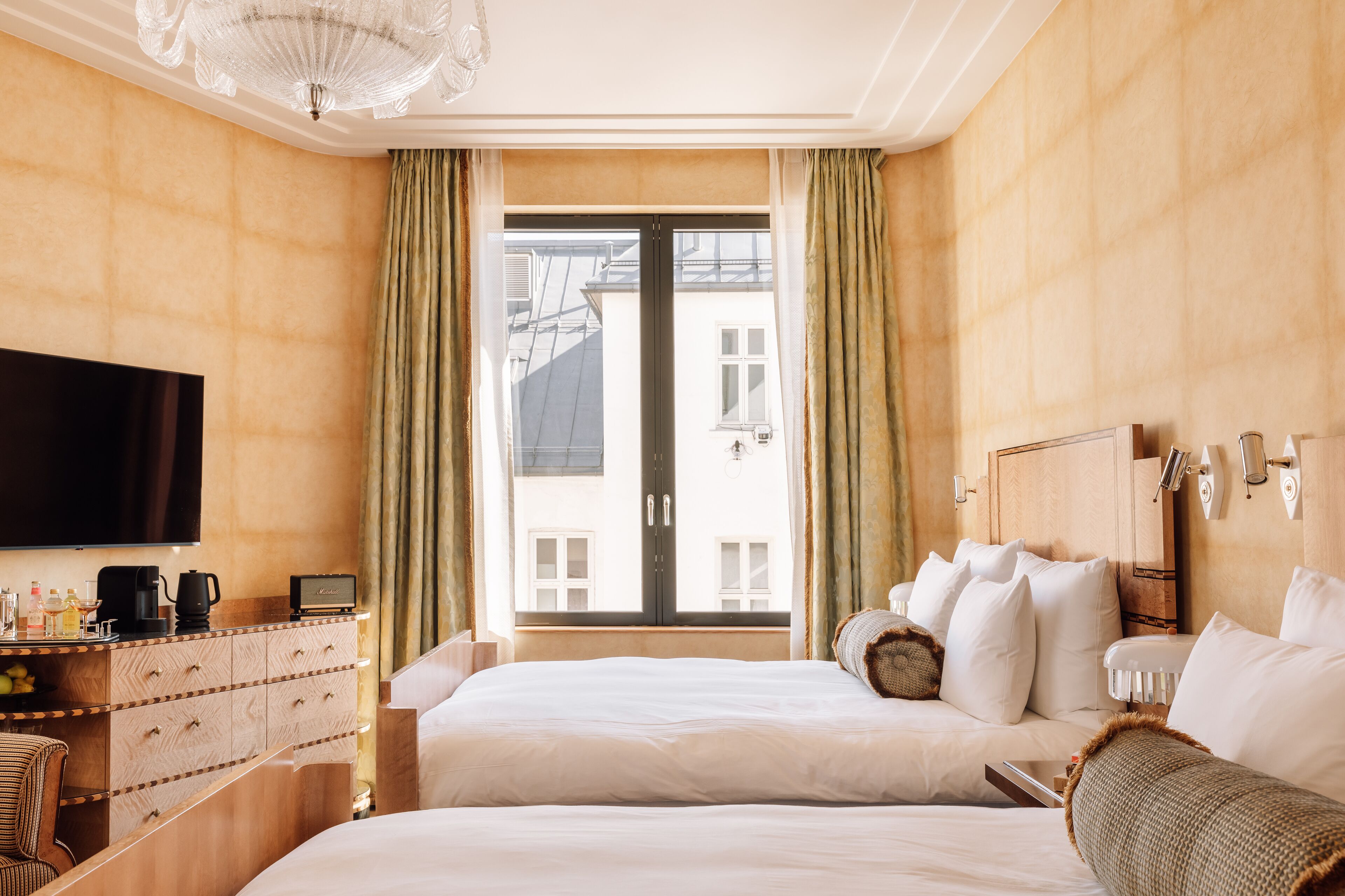 Habitación de hotel con una cama grande, un escritorio, un televisor de pantalla plana, un fabricante de café y vistas a edificios.