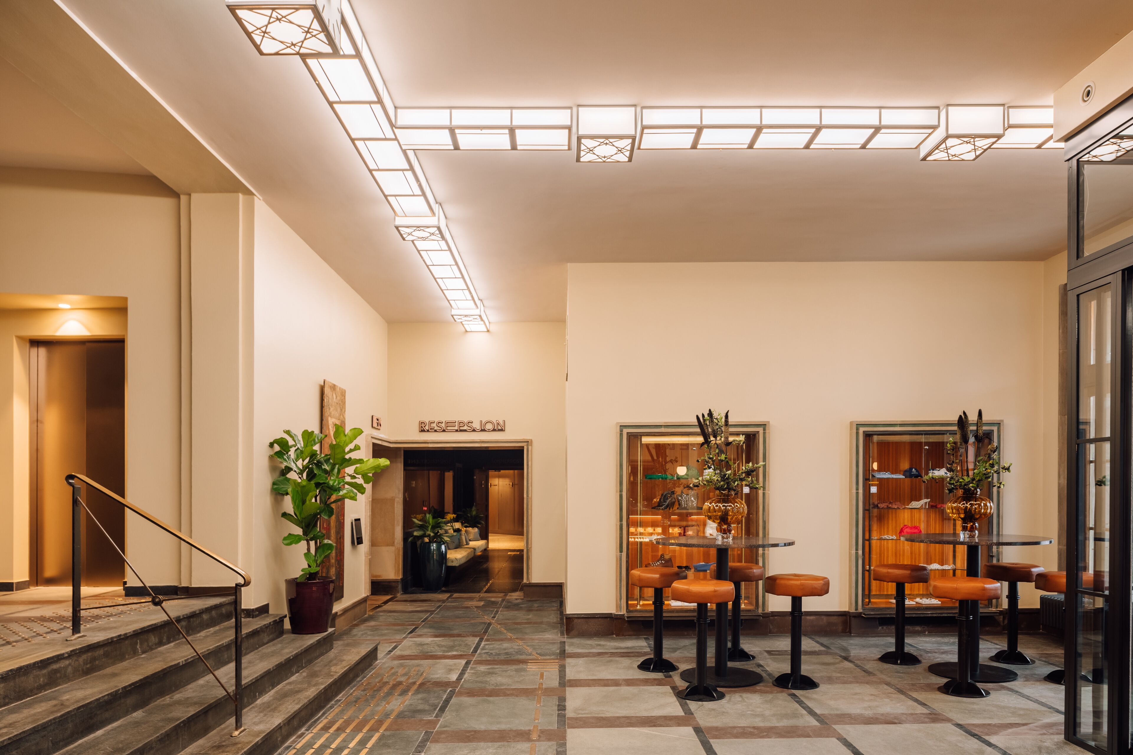 A hotel lobby with a reception desk, seating area, and a staircase.
