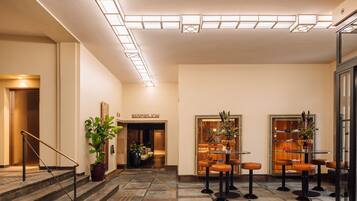 A hotel lobby with a reception desk, seating area, and a staircase.