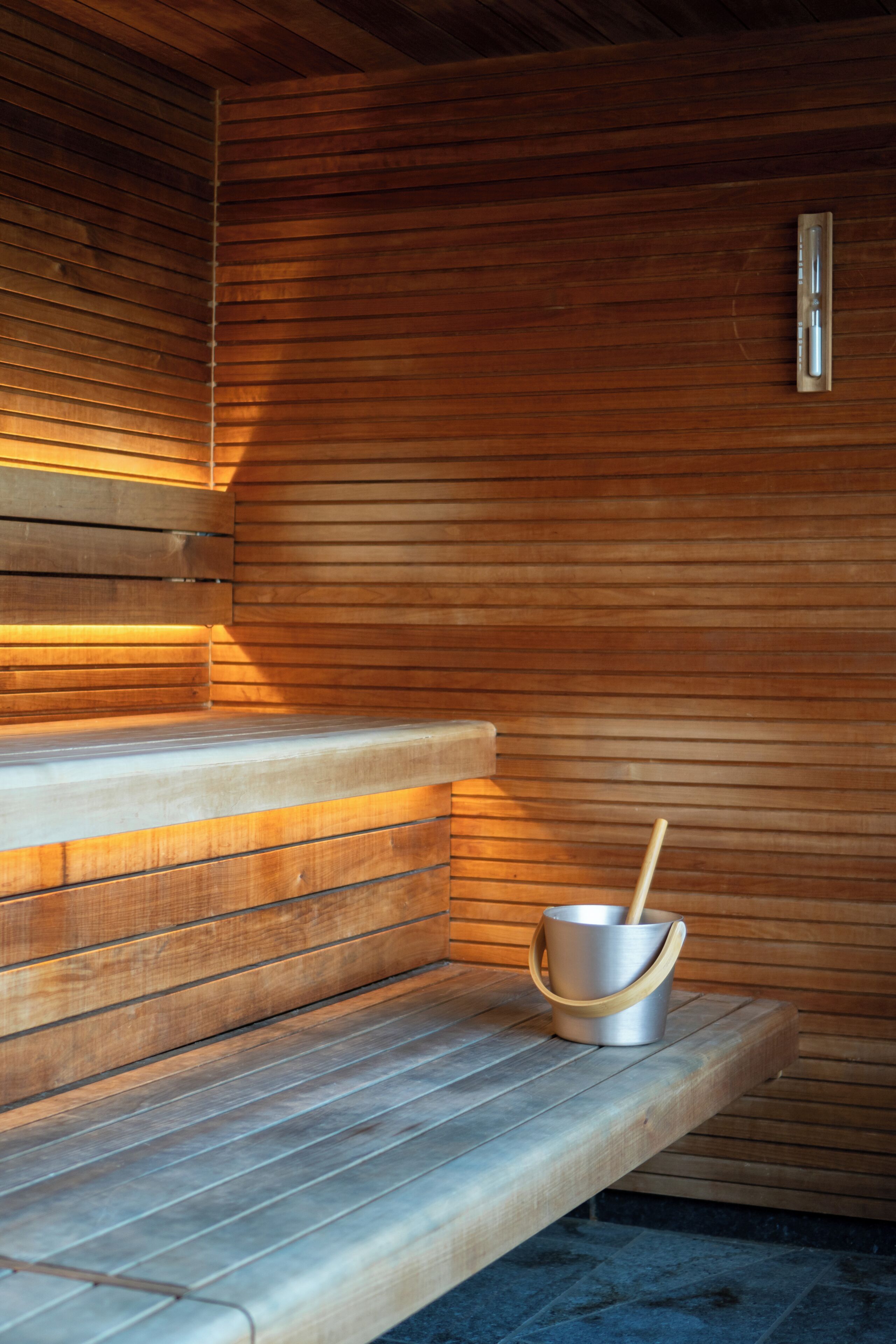 Una sauna con bancos de madera y un cubo de metal.