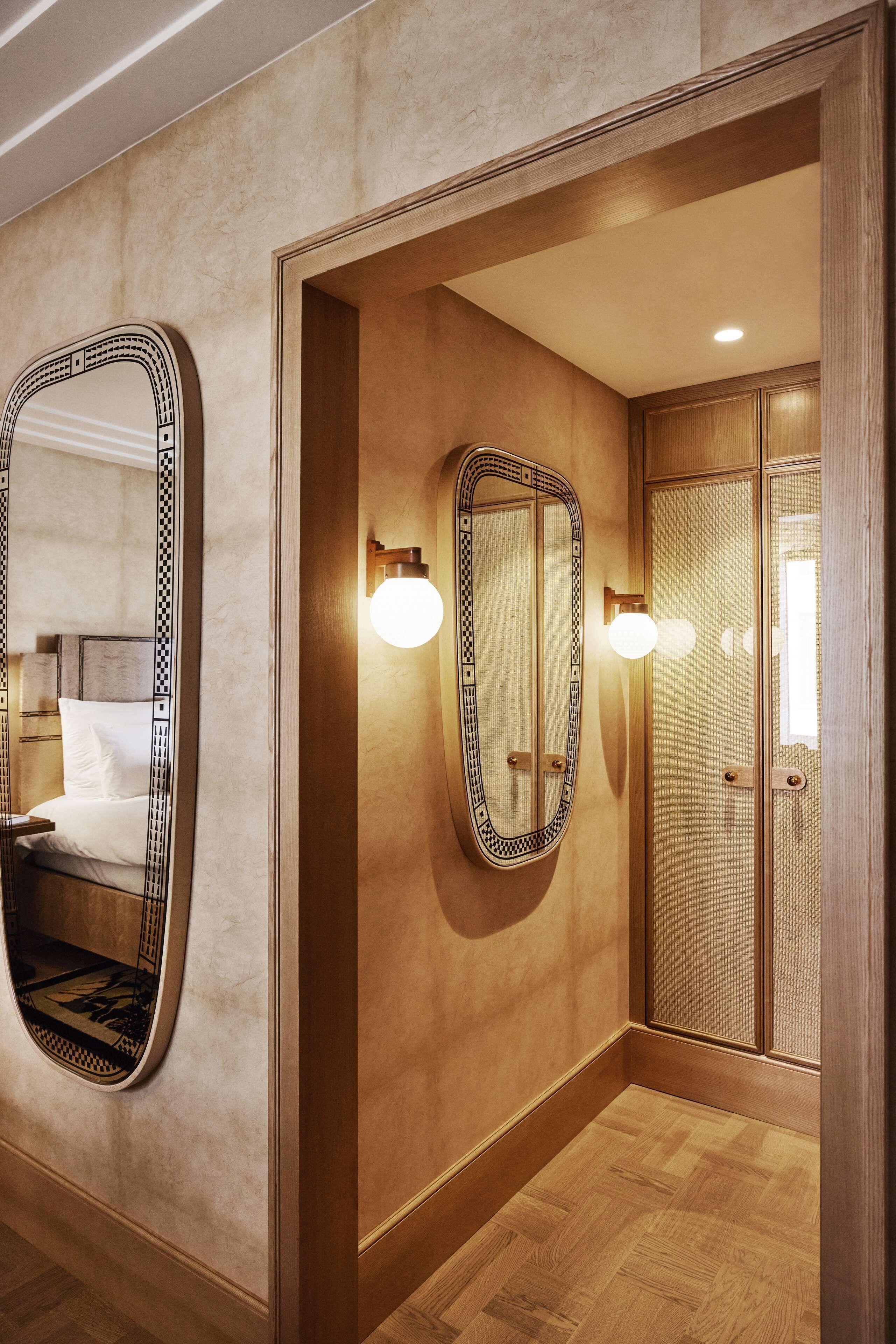 Una habitación de hotel con un espejo grande, una cama y un armario de madera.