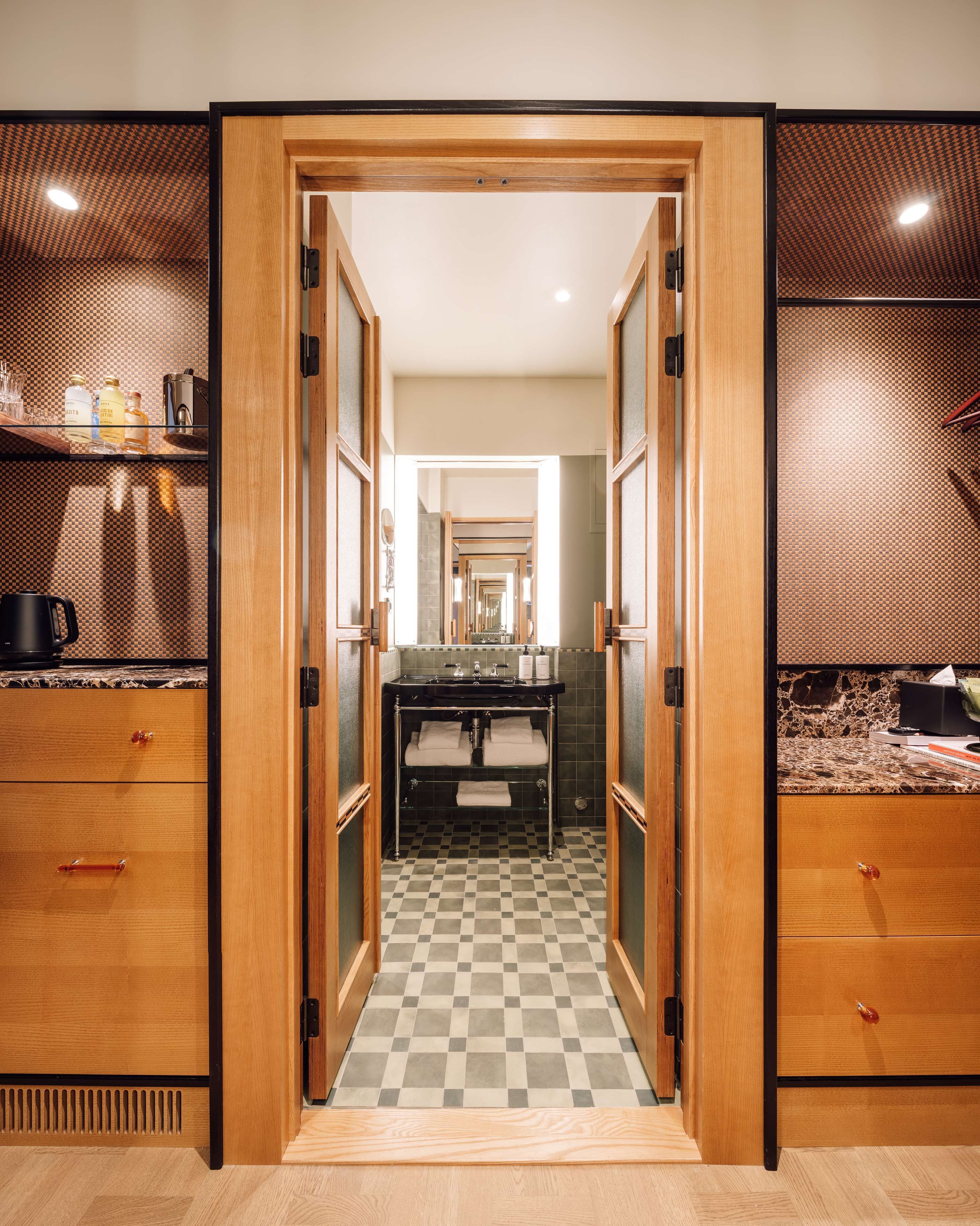 A modern bathroom with a checkered floor, wooden cabinetry, and a mirror.
