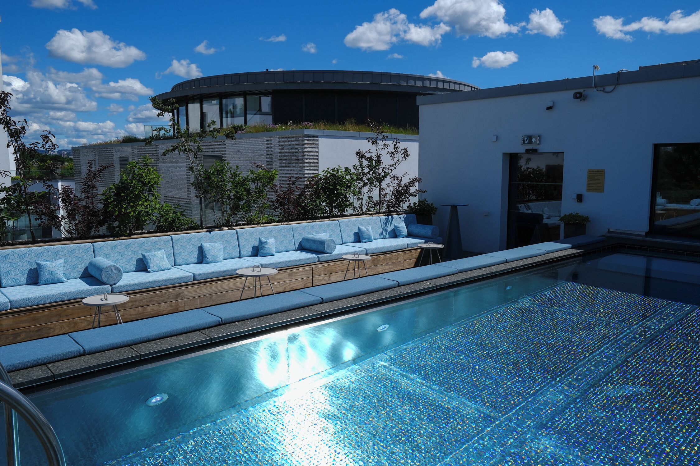 Un área de piscina moderna con asientos y una vista despejada del cielo.