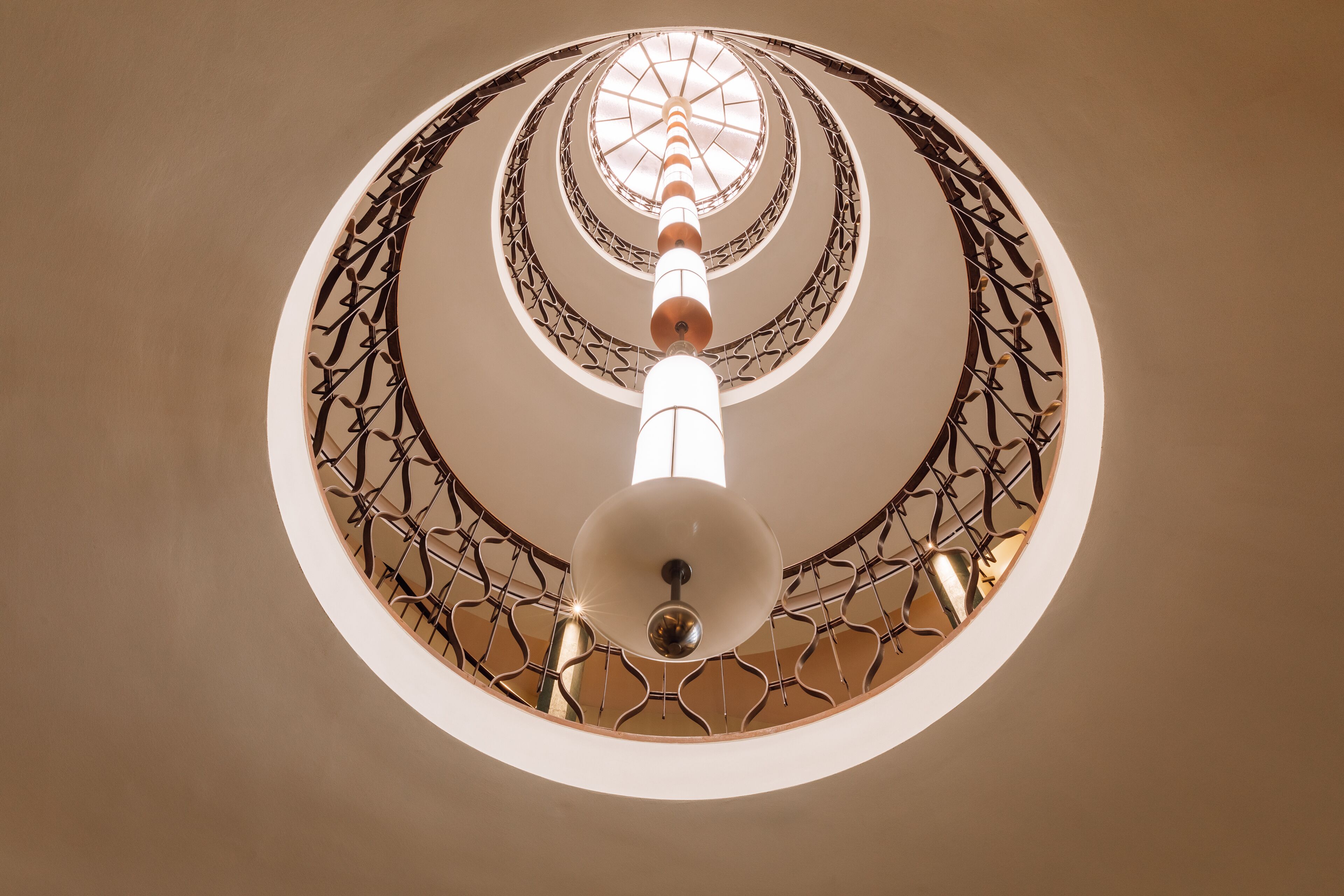 Eine Wendeltreppe mit einer zentralen Säule und einem geometrischen Metallgeländer.