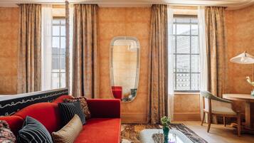 Una habitación con un sofá rojo, una mesa redonda y un espejo.