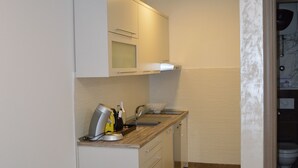 Una cocina compacta con armarios blancos, encimera de madera y horno integrado.