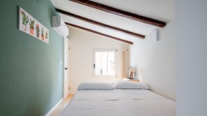 Um quarto com uma cama, uma janela e ar condicionado fixado na parede.