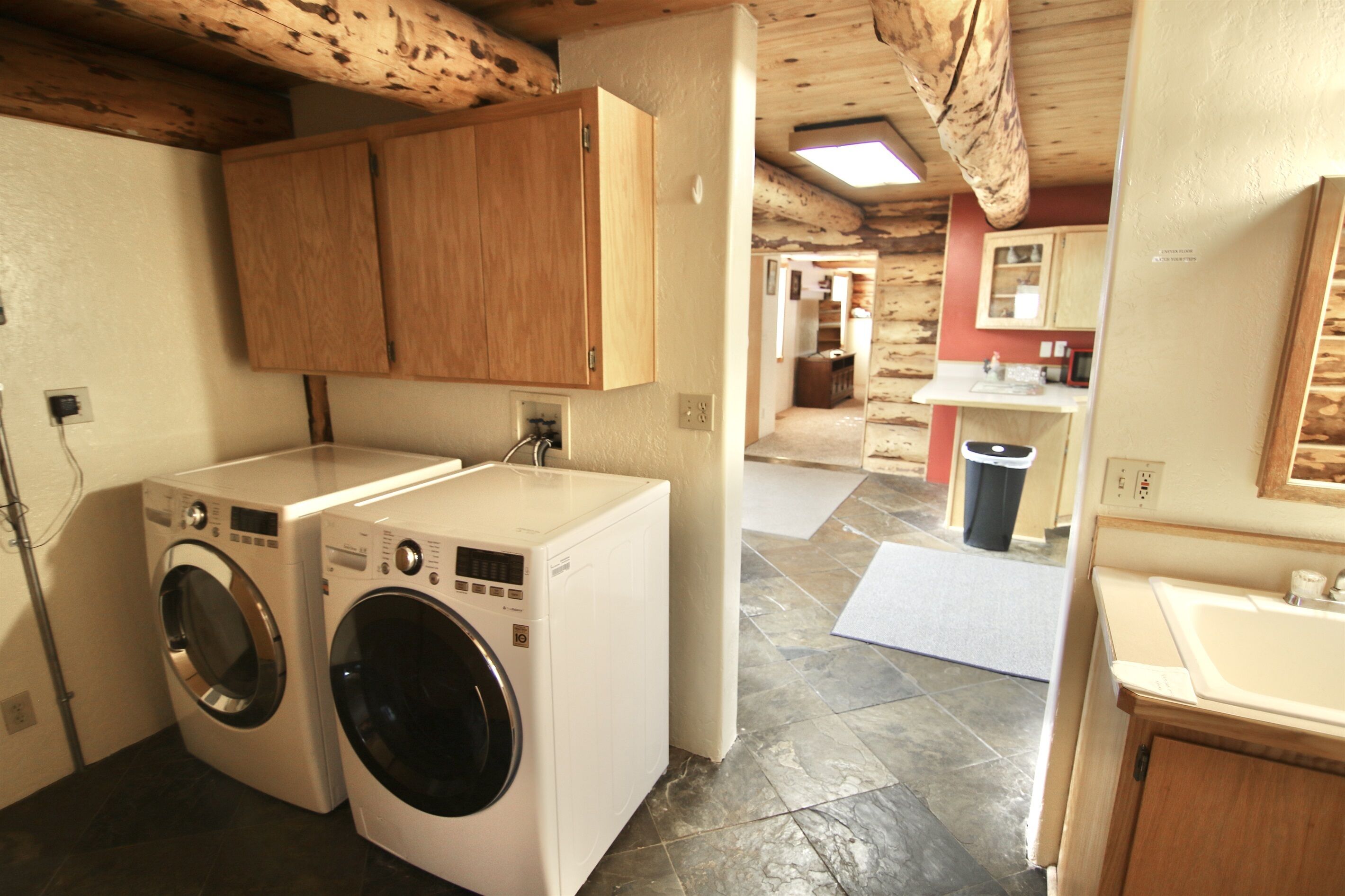 A laundry room with two washing machines, wooden cabinets, and a tiled floor.