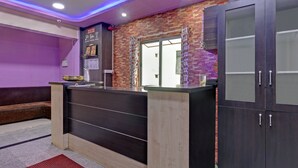 A reception area with a modern design, featuring a reception desk, a seating area, and a large window. - Guru Comfort, 100 m from Apollo Hospital (Bengaluru)