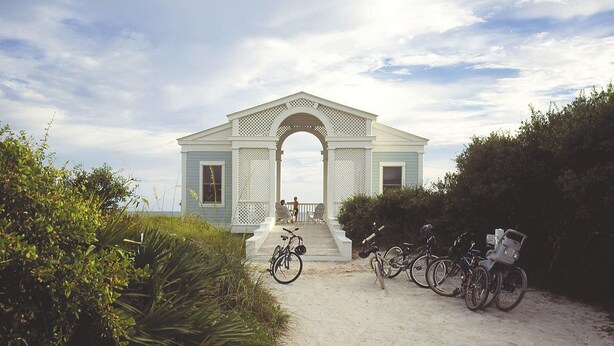 Un edificio con un portico bianco e un arco, immerso nel verde.