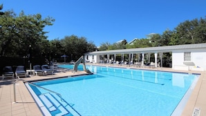 Una piscina con sedie a sdraio e una zona ombreggiata.