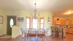 A dining area with a chandelier, wooden chairs, and a tiled floor. - Windsor Drive Monthly Rental (Cody)
