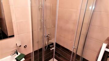 Een moderne badkamer met een douchecabine van glas, een wastafel met spiegel en een handdoekrek.
