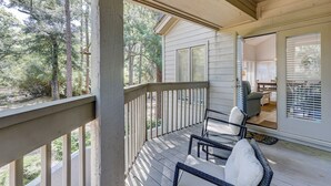 A covered porch with a railing, a dining area with a table and chairs, and a view of the surrounding trees. - Sunset Rentals | St. Andrews 1662 (Hilton Head Island)