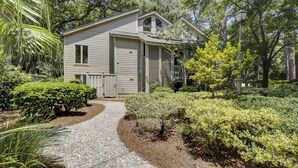 A two-story house with a gravel driveway leading to the front door. - Sunset Rentals | St. Andrews 1662 (Hilton Head Island)