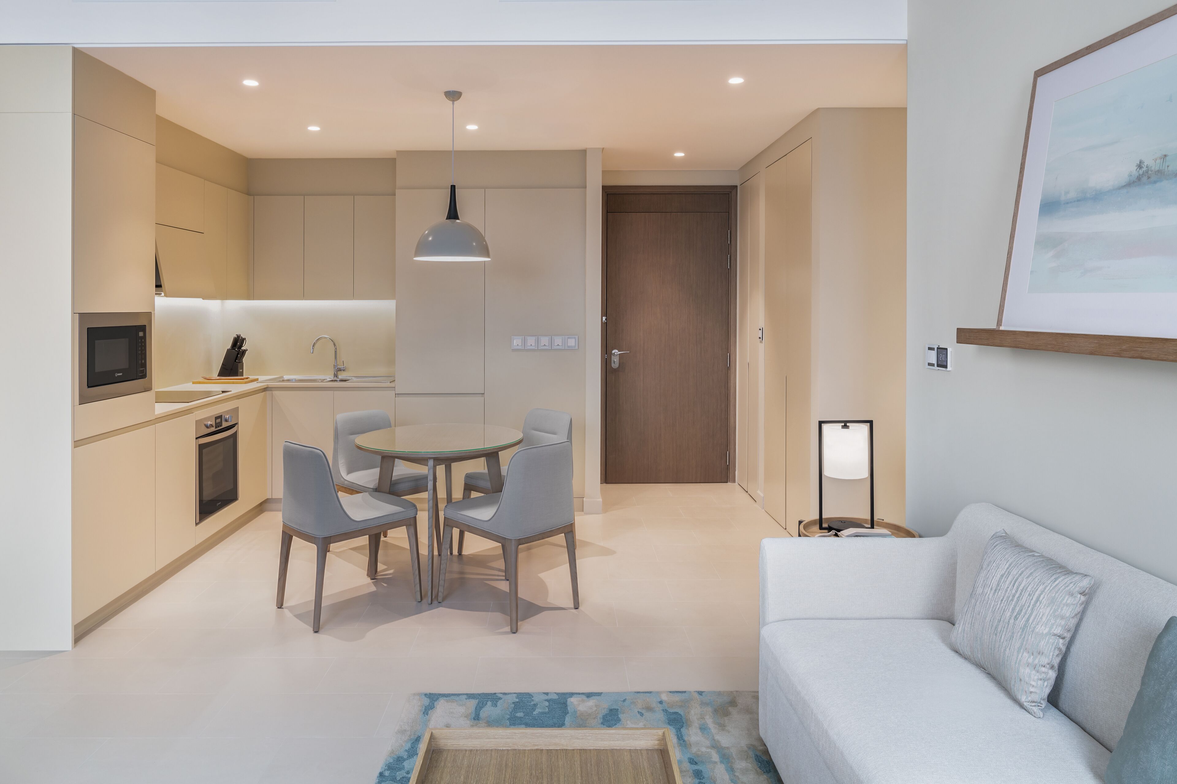 A modern kitchen with a dining area, a white sofa, and a framed picture on the wall.