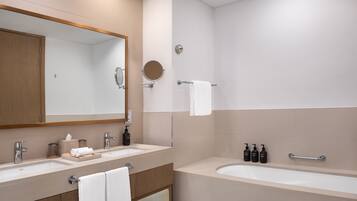 Uma casa de banho moderna com duas pias, um espelho grande e um espelho redondo, chuveiro e banheira.