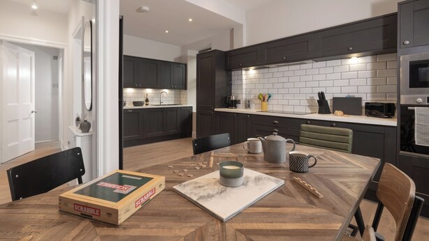 Une cuisine moderne avec des meubles de couleur sombre, un pare-feu en carreaux blancs et des appareils électroménagers en acier inoxydable.