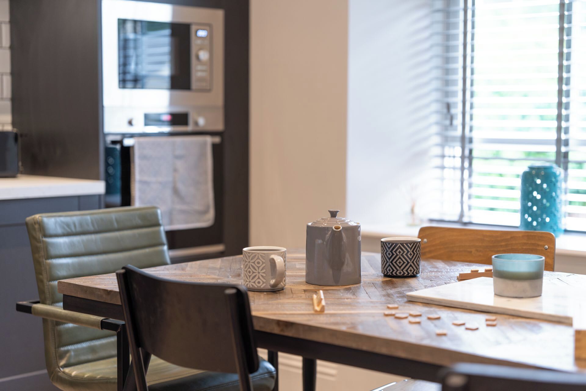 Una cocina moderna con una mesa de comedor, sillas y una ventana con persianas.