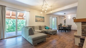 Ein geräumiges Wohnzimmer mit einer Eckcouch, einem Essbereich mit Tisch und Stühlen sowie einem Kamin.