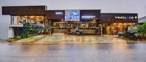 A hotel with a modern design, featuring a prominent 'Hotel' sign, a 'Residency' section, and a 'Woodland' furniture store.